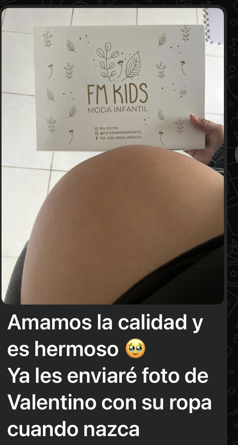 Fotografía compartida por una clienta: una futura mamá sostiene un ajuar de FM Kids.